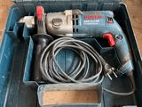 une perceuse filaire dans une boîte à outils posée par terre