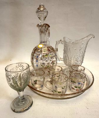 Des bouteilles et des verres sont posés sur un plateau, avec une carafe en arrière-plan.