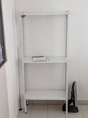 une étagère blanche sur laquelle se trouve un livre, près d'une fenêtre
