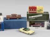 Plusieurs petites voitures sont posées sur des cartons, sur une surface blanche.