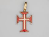 un pendentif en forme de croix rouge et dorée, orné d'une croix blanche