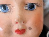 a close up of a doll with blue eyes and a red nose