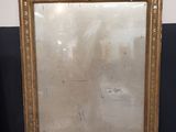 un miroir ancien à cadre doré posé sur un sol en marbre