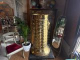 a tall gold vase sitting on a pedestal in a room