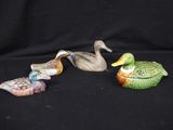three small ceramic ducks sitting on top of each other on a black surface