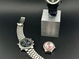 two watches and a watch stand on a black surface