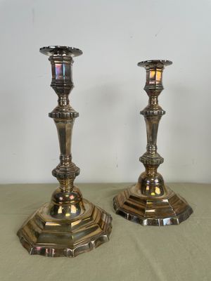 une paire de bougeoirs en argent posés sur une table, sur fond blanc