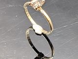a gold ring with a diamond and a pearl on it