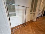 un portant métallique sur lequel sont suspendus des vêtements, dans une pièce