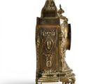 a gold clock on a stand with a bird on top