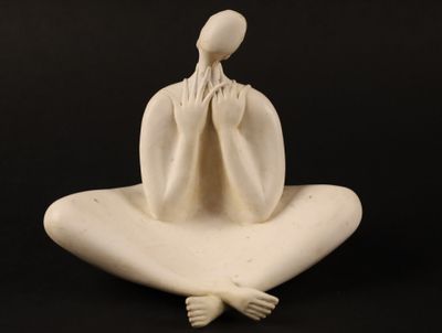 sculpture représentant une femme assise sur un oreiller, les mains sur le visage