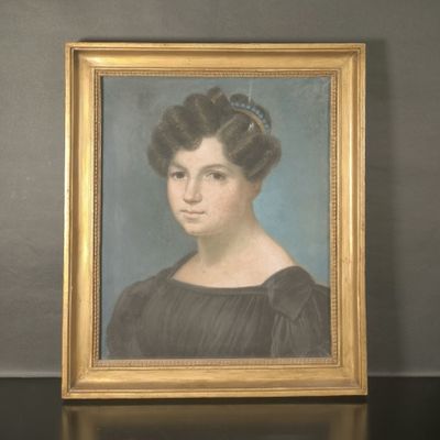portrait d'une femme en robe noire, dans un cadre doré, posé sur une table noire
