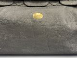 the back of a black purse with a gold button on it