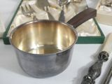 a silver bowl with spoons and spoon rest on a table