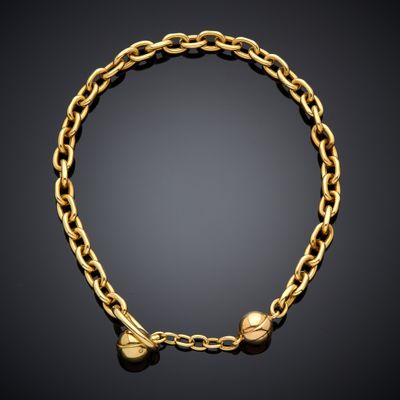 a gold bracelet with two small bells on a black background