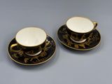 un service de tasses à café et soucoupes noires et dorées