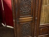 une armoire en bois ornée de sculptures, placée dans un coin de la pièce