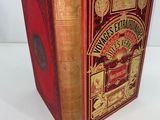 an old book with a red cover sitting on top of a white table