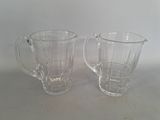 une paire de mugs en verre transparent posés sur une table blanche