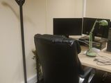 a desk with a chair and a lamp in the corner