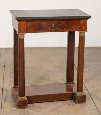 une vieille table en bois avec un plateau en marbre, posée sur un parquet