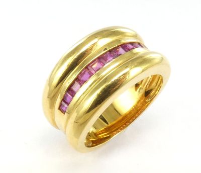 une bague en or jaune sertie de saphirs roses sur fond blanc