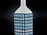 un vase blanc orné de carrés bleus sur un fond noir