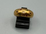une bague en or posée sur un socle noir, sur une surface blanche