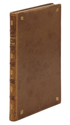 an old book with a brown cover sitting on top of a white surface