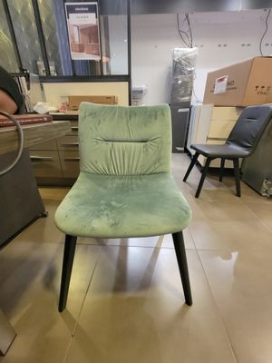 une chaise verte placée dans une pièce où se trouvent d'autres chaises