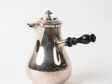 une cafetière en argent avec une poignée noire sur fond blanc