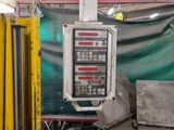 a picture of a machine in a factory with a green tarp in the background