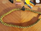 a yellow and black braided belt on a wooden table