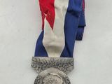 an image of a silver medal with a red, white and blue ribbon