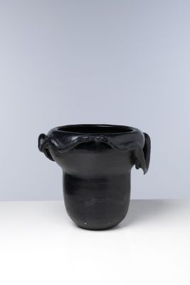 une image représentant un vase noir posé sur une table blanche