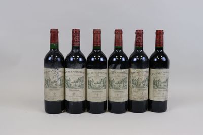 six bottles of wine are lined up on a white surface