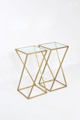 une paire de tables d'appoint dorées avec des plateaux en verre