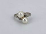 a close up of a white pearl and diamond ring on a white surface