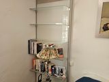 une étagère en verre avec des livres et une lampe dans un coin