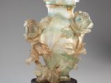 un vase vert orné de fleurs, posé sur un socle
