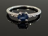 a close up of a ring with a blue sapphire and diamonds