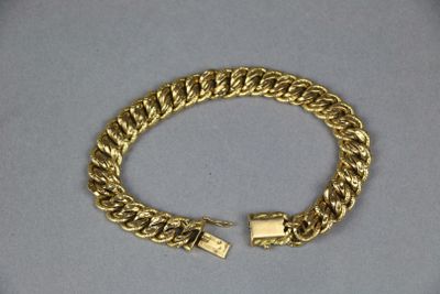 a close up of a gold bracelet on a white surface