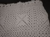 a white crocheted table cloth with a cross on it