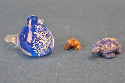un oiseau bleu posé à côté de deux petites figurines sur une table