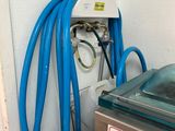 un tuyau bleu fixé au mur, à côté d'un réservoir d'eau