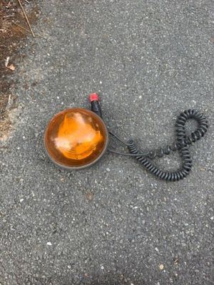 une lumière orange posée par terre à côté d'un cordon