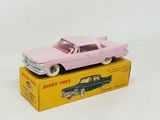 une petite voiture rose posée sur une boîte jaune, elle-même posée sur une surface blanche
