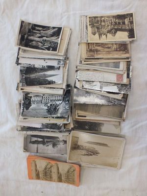 une pile de vieilles photos posée sur un lit, à côté d'un livre