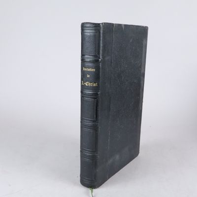 un livre noir orné de lettres dorées, posé sur une surface blanche