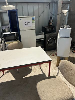 plusieurs chaises et une table dans une pièce, avec un réfrigérateur à l'arrière-plan